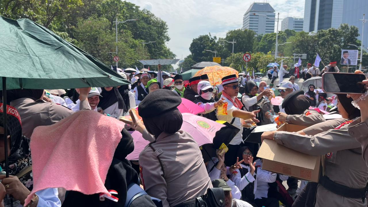 Polisi Bagikan Air Mineral dan Roti kepada Massa Aksi Damai Guru di Silang Selatan Monas